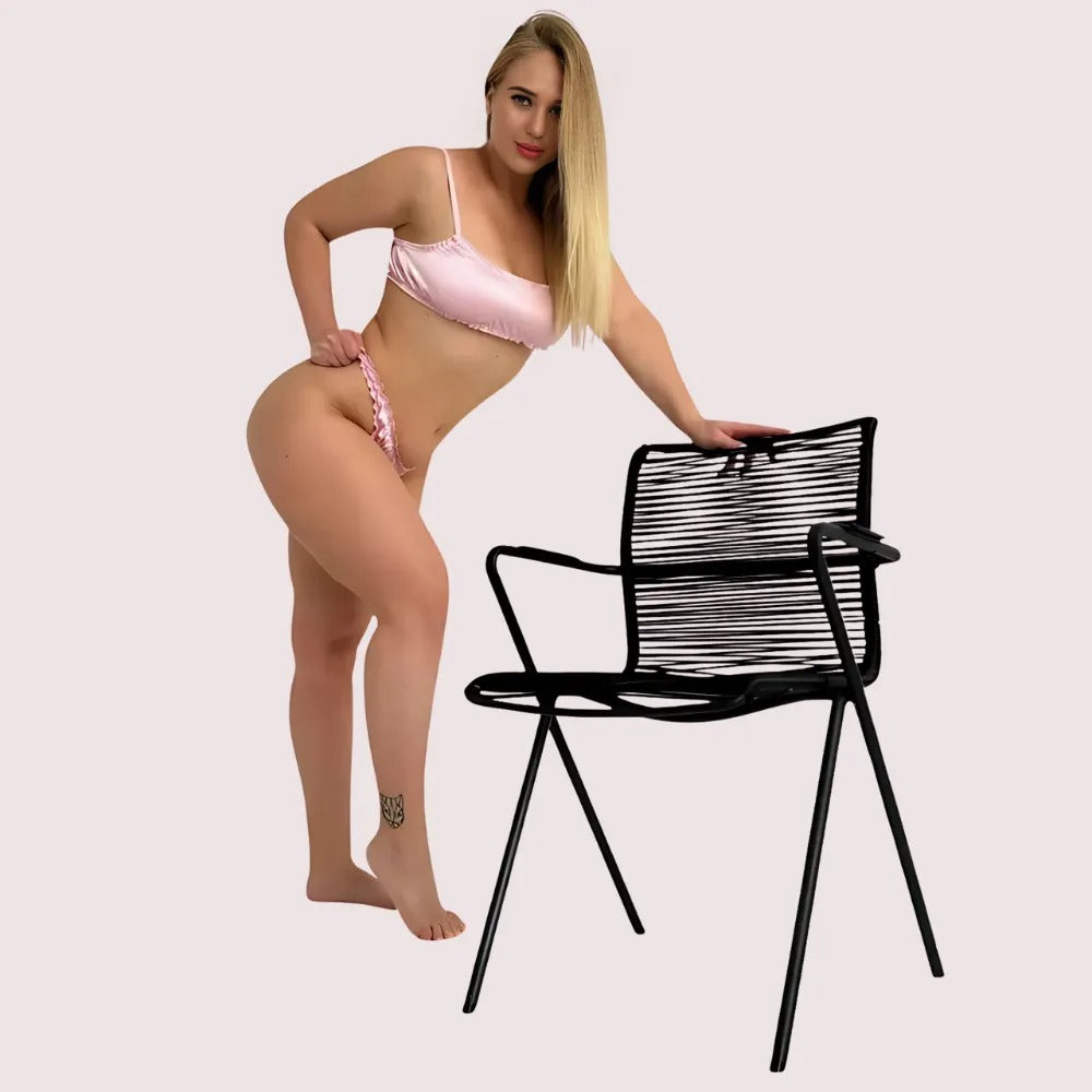 Pure silk lingerie set in blush pink, showing comfortable elastic fit and soft satin finish while posing beside a chair.